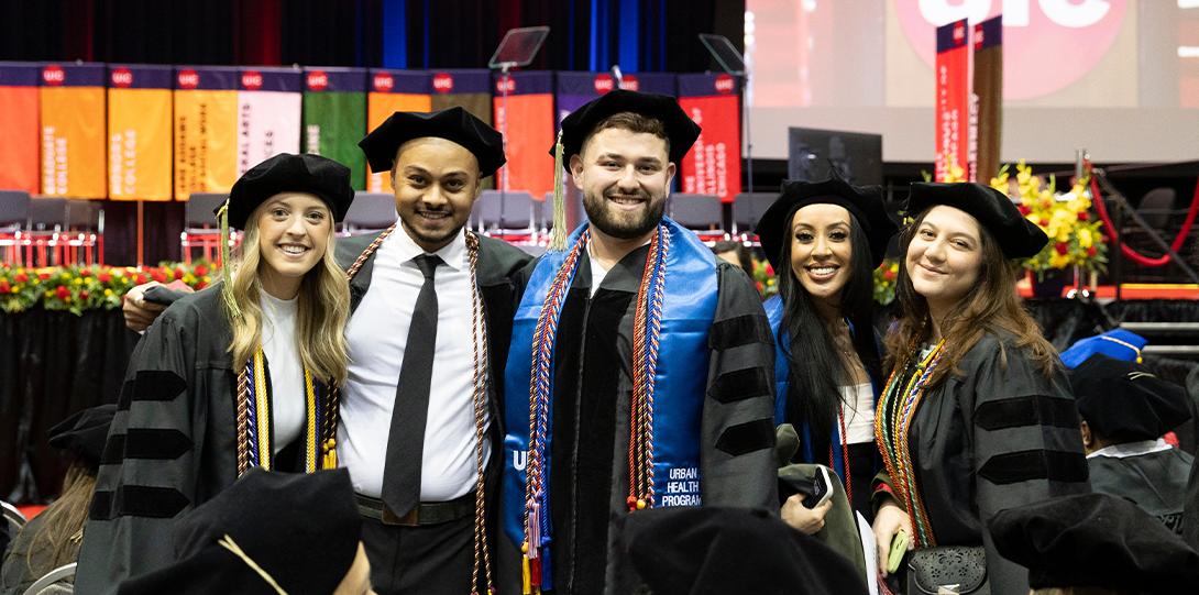 A group of five PharmD graduates pose inside in the UIC Dorin Forum