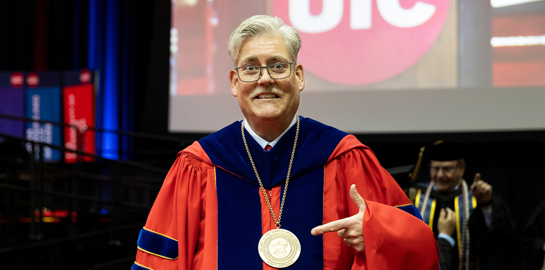 Dean Schumock in his regalia pointing to his gold medallion