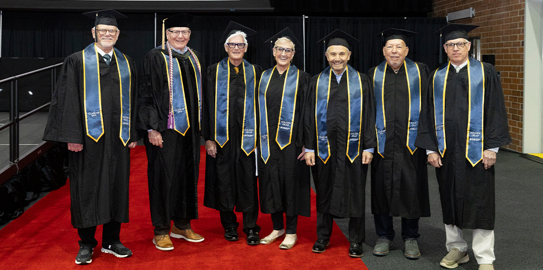 The Class of 1975 Golden Grads pose in their regalia inside UIC Dorin Forum